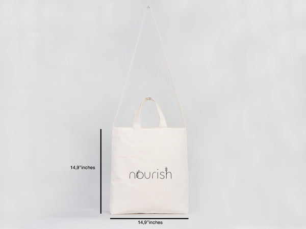 White tote bag with 'nourish' branding and measurements on a light gray background